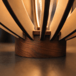 Gros plan sur le socle en noyer massif et l'assemblage de la Lampe Flamme fabriquée artisanalement par Création50.